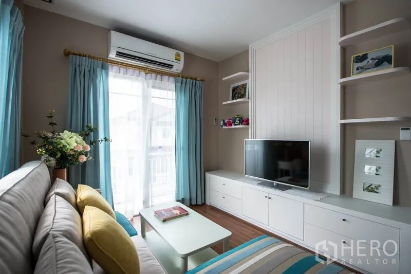 Detached House for sale in Bang Kapi, Bangkok - Upstairs family room with TV unit, wall shelving and blue curtains.