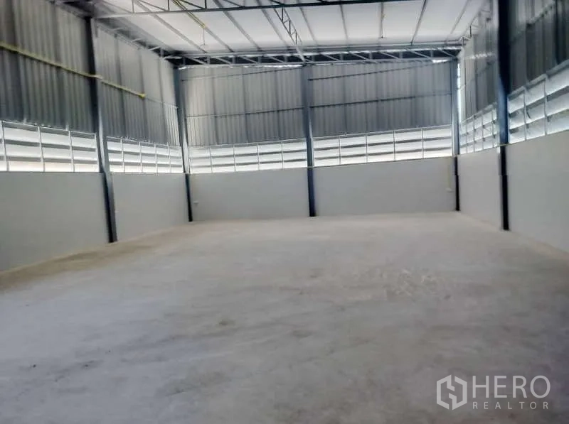 Warehouse for rent in Pathum Thani - Spacious warehouse interior with high ceiling, steel beams and smooth concrete floor.