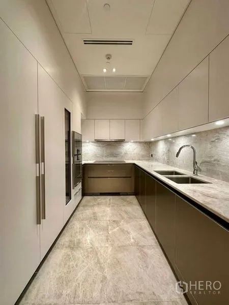 Condominium for rent or sale - Sleek galley kitchen with stone countertops, under-cabinet lighting and a double sink.