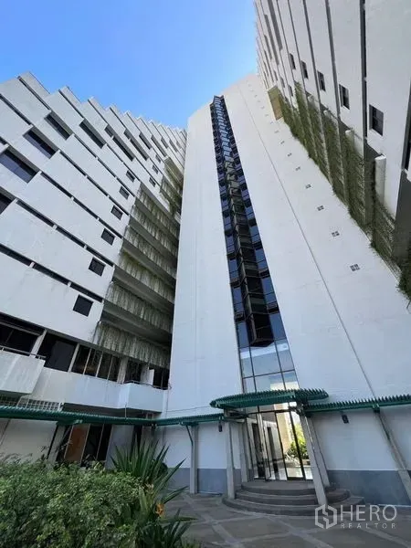 คอนโด ให้เช่าหรือขายในWatthana, Bangkok - ภายนอกอาคารคอนโดสูง พร้อมทางเข้าแก้วและผนังสีขาว