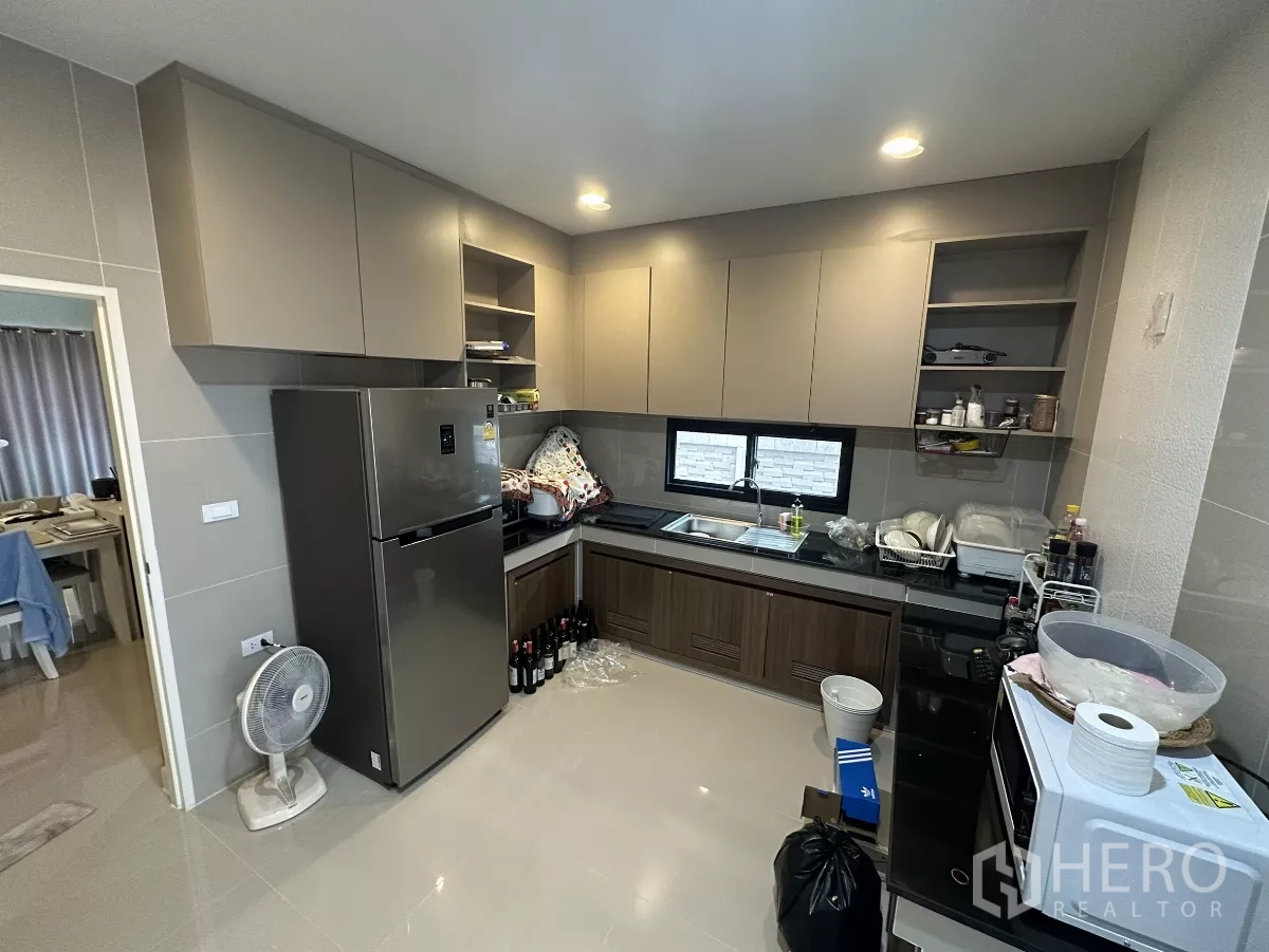 บ้าน ให้เช่าหรือขายในLam Luk Ka, Pathum Thani - ครัวรูปตัว U พร้อมตู้เก็บของบน–ล่าง หน้าต่างคู่ ตู้เย็น และผนังกระเบื้อง