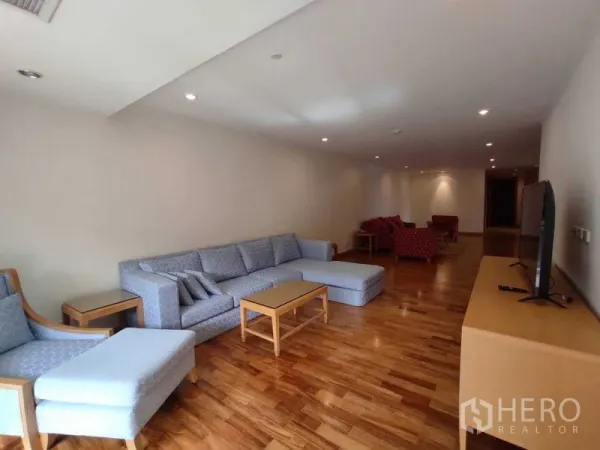 คอนโด ให้เช่าในKhlong Toei, Bangkok - ห้องนั่งเล่นแบบเปิดโล่งยาว มีโซฟาขนาดใหญ่และชุดเก้าอี้สีแดงด้านในสุด