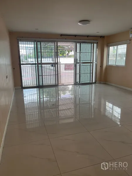 联排别墅 出租在Huai Khwang, Bangkok - 宽阔一层起居区，落地推拉门与安全护栏，光亮瓷砖地。