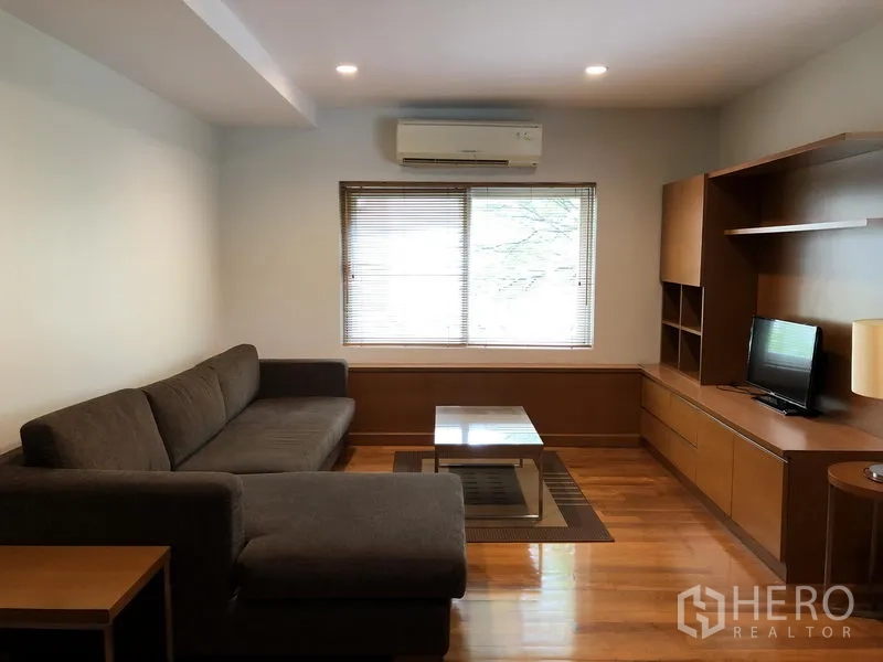 Detached House for rent in Watthana, Bangkok - Cozy family room with L-shaped sofa, built-in media cabinet and wood floors.