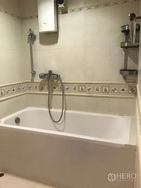 Condominium for rent in Watthana, Bangkok - Tiled bathroom with built-in bathtub and handheld shower.
