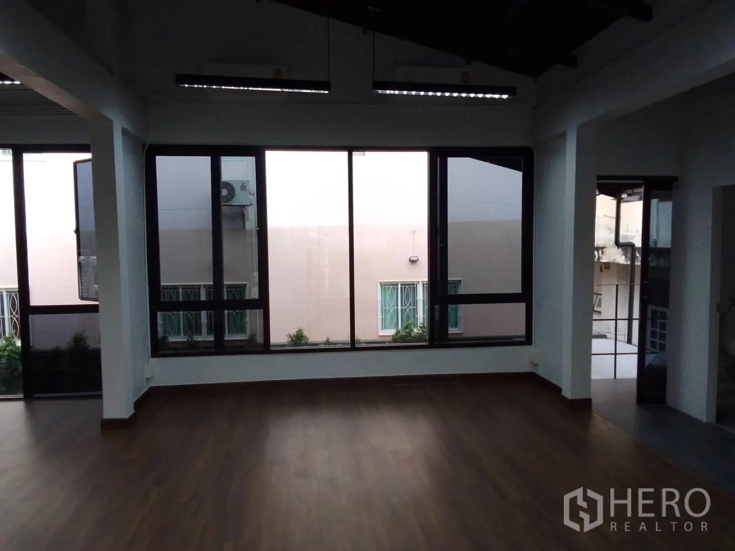 Home Office for rent in Wang Thonglang, Bangkok - Spacious office room with wood flooring and wide windows to neighboring buildings