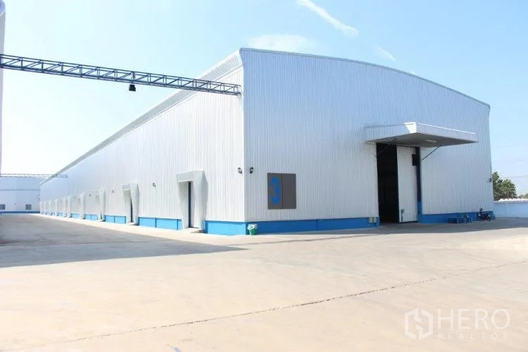 Warehouse for rent in Lat Lum Kaeo, Pathum Thani - Corner view of a modern warehouse with high roller door, canopy, and spacious truck yard.