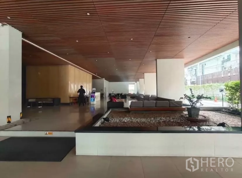 Condominium for rent in Chatuchak, Bangkok - Modern lobby with wood ceiling, seating area and landscaped feature.