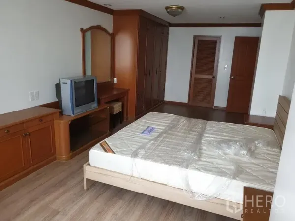 Condominium for rent in Watthana, Bangkok - Spacious master bedroom with built-in wardrobes, dressing table and wood cabinetry.
