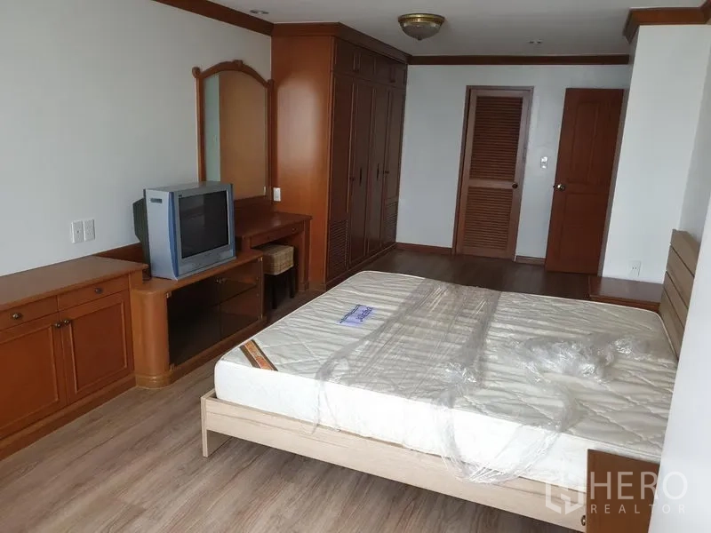 Condominium for rent in Watthana, Bangkok - Spacious master bedroom with built-in wardrobes, dressing table and wood cabinetry.