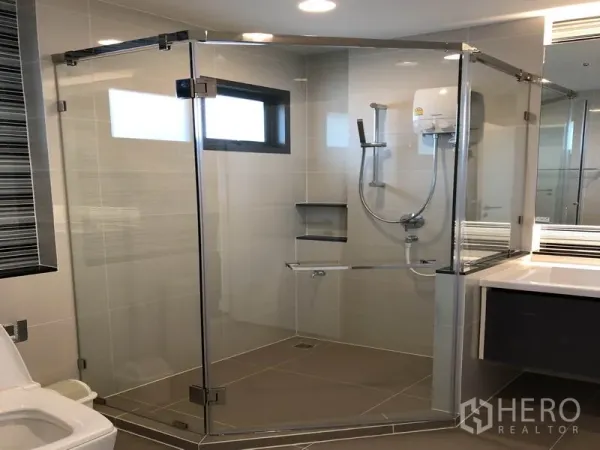 Detached House for rent or sale in Bang Kapi, Bangkok - Contemporary bathroom with frameless glass shower enclosure and wall-mounted water heater.