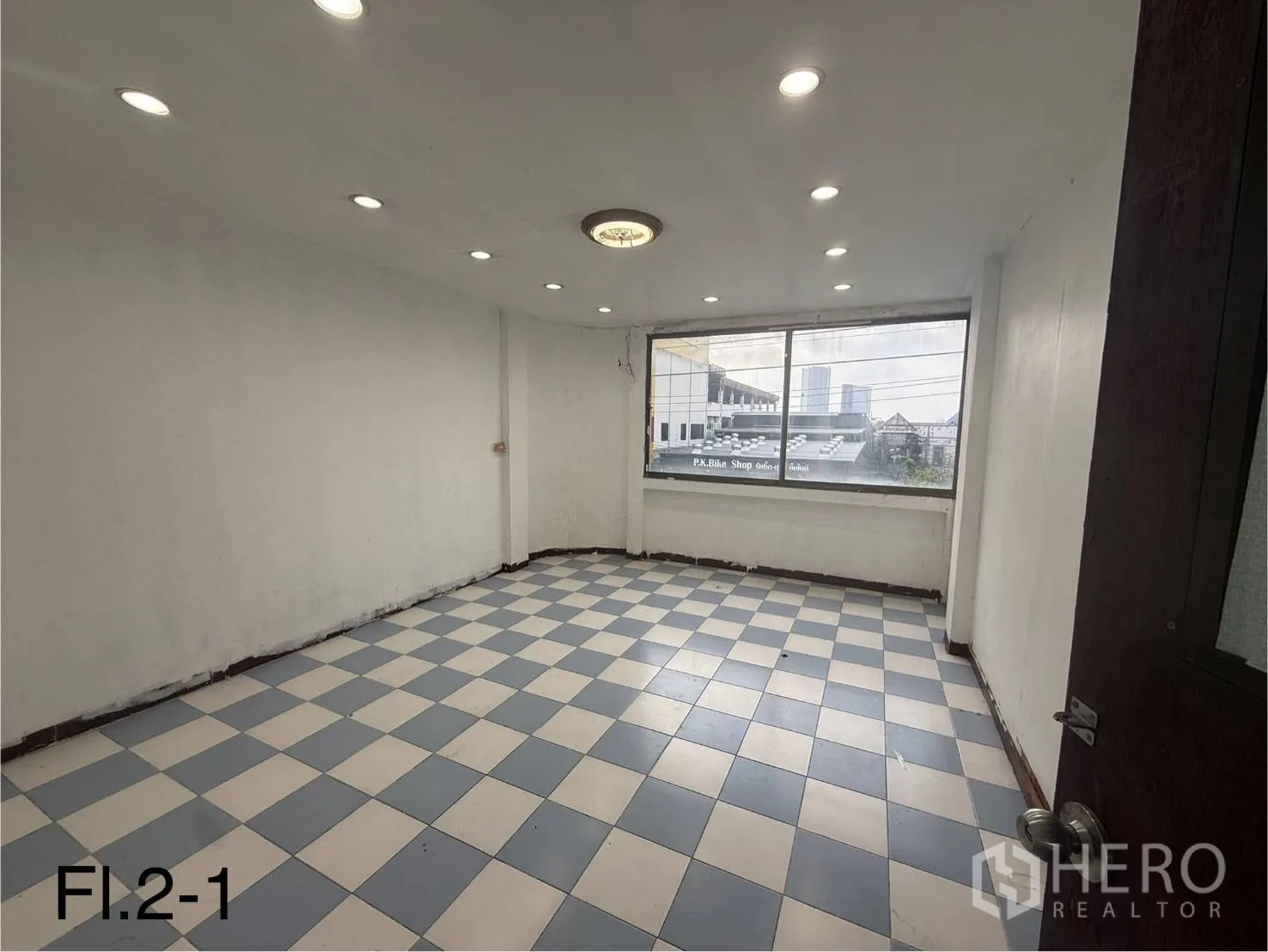 Shophouse for rent in Bang Na, Bangkok - Bright second-floor room with blue-and-white checkered tiles and a wide window facing the street.