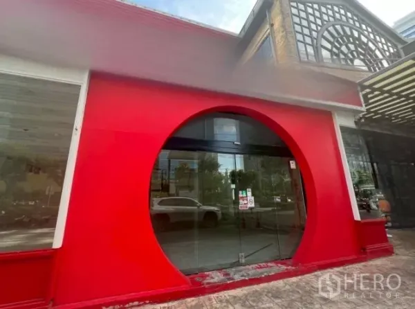 零售空间 出租 - 曼谷Khlong Toei街边商铺外立面，红色外墙与圆形玻璃入口，醒目显眼。