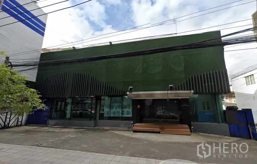 零售空间 出租在Suan Luang, Bangkok - 临街零售建筑，绿色外立面，大面积玻璃橱窗与小前院。