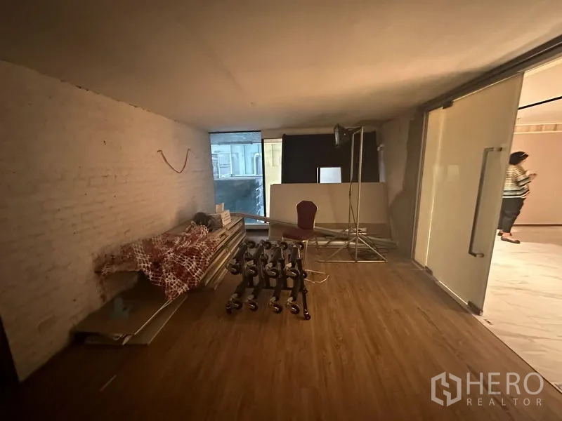 Office Space for rent in Khlong Toei, Bangkok - Flexible studio room with sliding glass door, wood floors and stored equipment along one side.