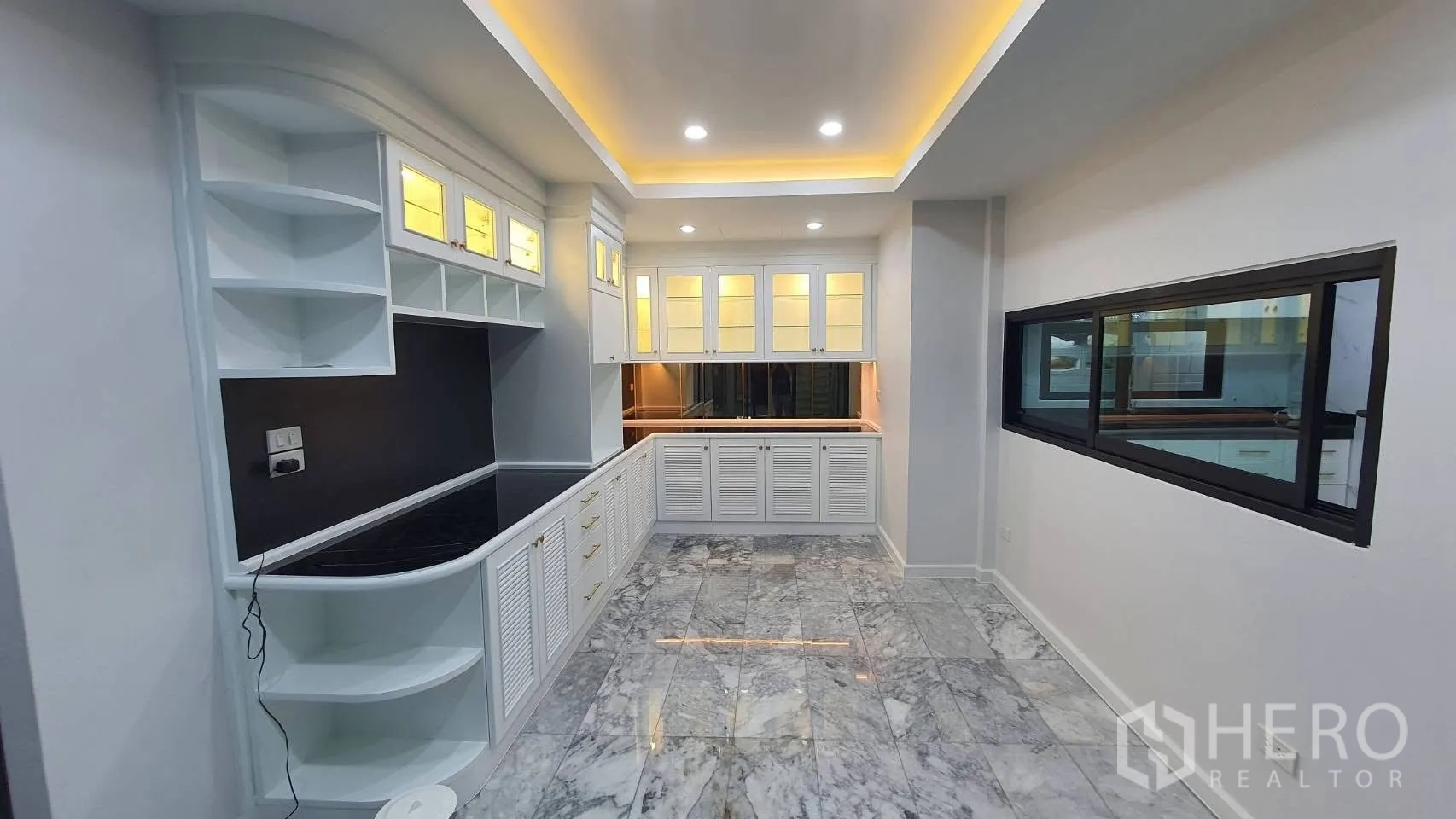 独栋房屋 for rent in Lat Phrao, Bangkok - 白色储物间/备餐柜，暖色灯光与大理石地面。