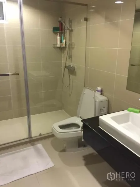คอนโด ให้เช่าในHuai Khwang, Bangkok - ห้องน้ำสมัยใหม่พร้อมตู้กระจกอาบน้ำ อ่างล้างหน้าแบบแขวนผนัง และกระเบื้องโทนอบอุ่น
