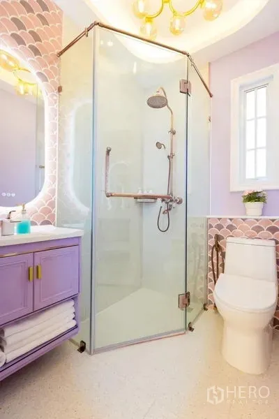 联排别墅 出租在Lat Phrao, Bangkok - 浴室设玻璃转角淋浴间，薰衣草色洗手台与圆镜，柔和马赛克墙面。