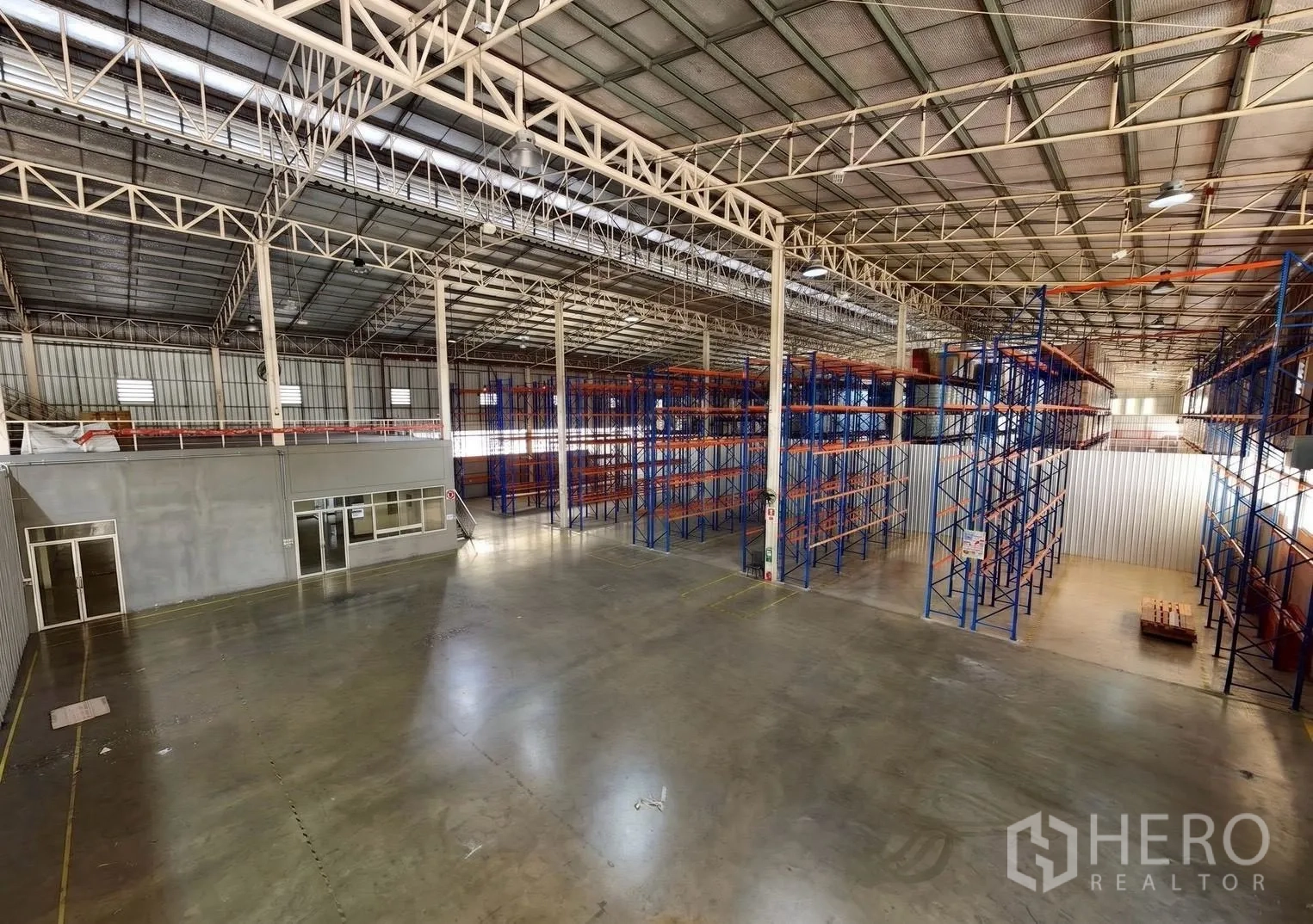 Warehouse for rent in Bang Sue, Bangkok - Spacious warehouse interior with steel truss roof, polished floor, office rooms, and pallet racking.