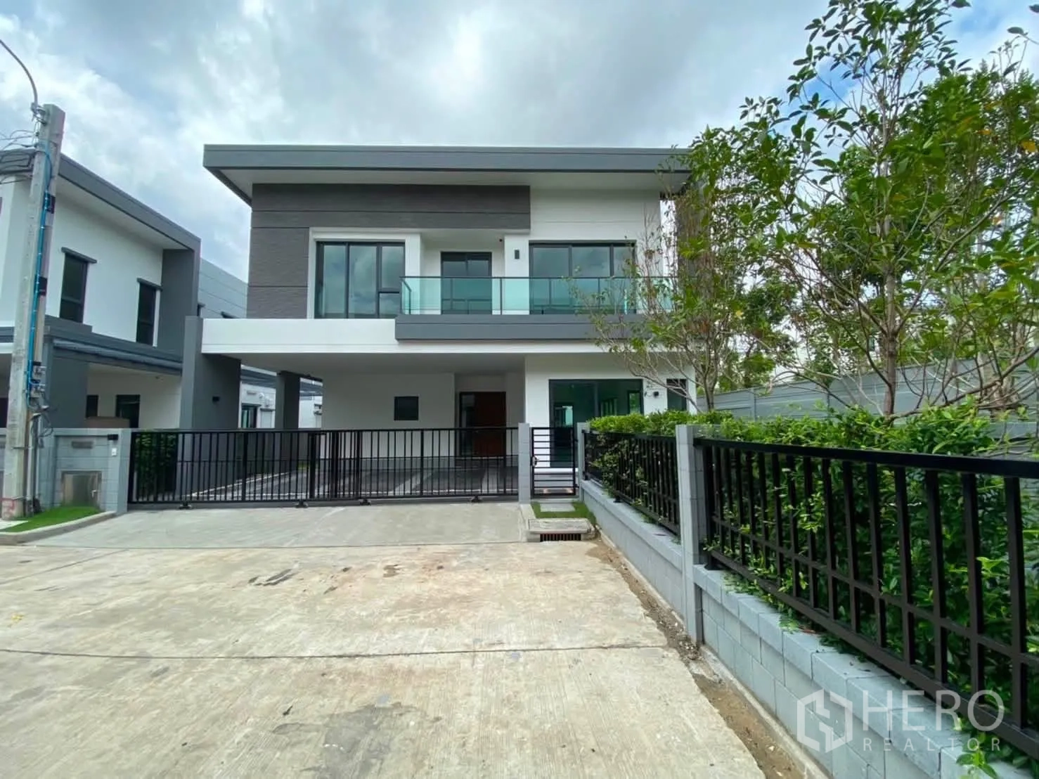 บ้านเดี่ยว for rent or sale in Prawet, Bangkok - ภายนอกบ้านเดี่ยวสองชั้นสมัยใหม่ มีระเบียง กระตูรั้วทางรถ และสวนจัดแต่ง