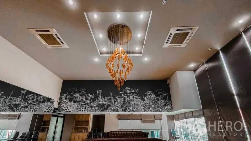 Office Space for rent in Lak Si, Bangkok - Ceiling detail with recessed lighting, cassette air-conditioners and gold chandelier above office with mural wall and wide windows.