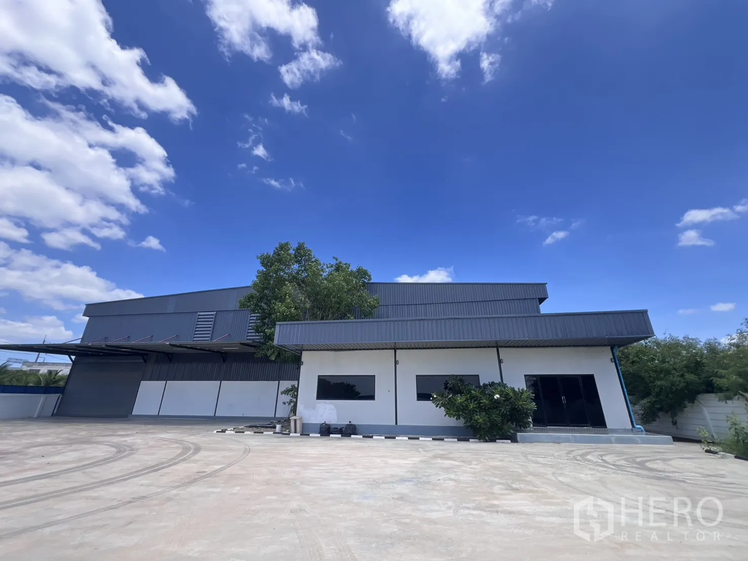 Warehouse for rent in Mueang Samut Sakhon, Samut Sakhon - Front elevation of the warehouse and office with wide driveway.