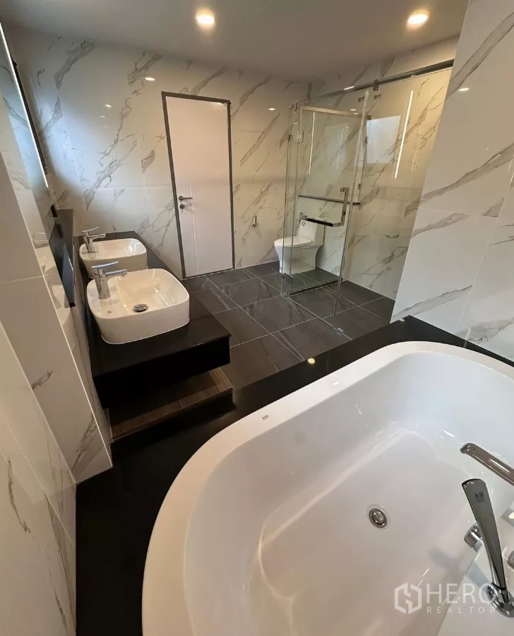Detached House for rent in Bang Phli, Samut Prakan - Luxury bathroom with bathtub, twin basins, glass shower, and marble wall tiles.