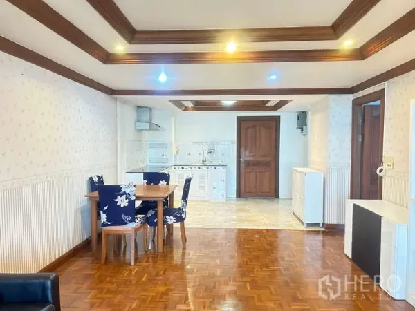 Condominium for sale in Huai Khwang, Bangkok - Spacious living–dining room with parquet flooring, coffered ceiling lighting, and a compact kitchen.