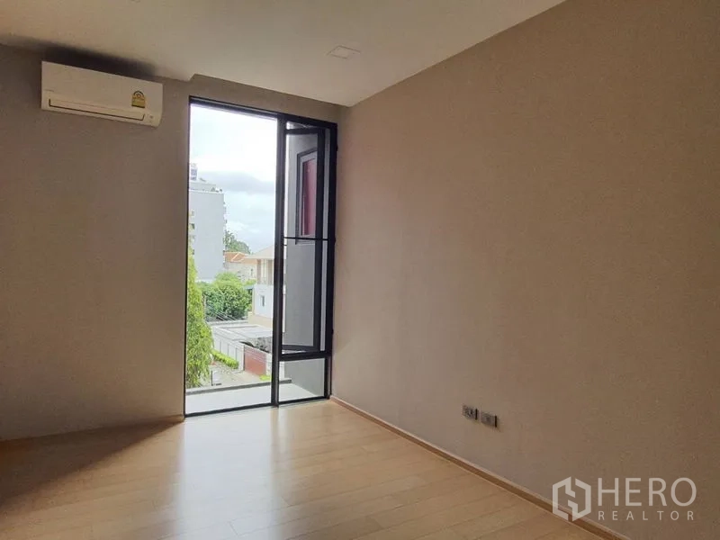 Condominium for sale in Huai Khwang, Bangkok - Second bedroom with floor-to-ceiling door window, air conditioner and neighborhood view.