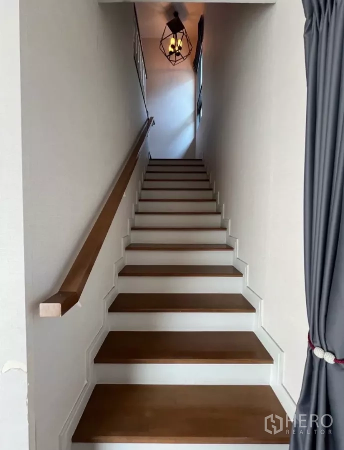 Detached House for rent in Prawet, Bangkok - Staircase with wooden treads, handrail and a modern pendant light.