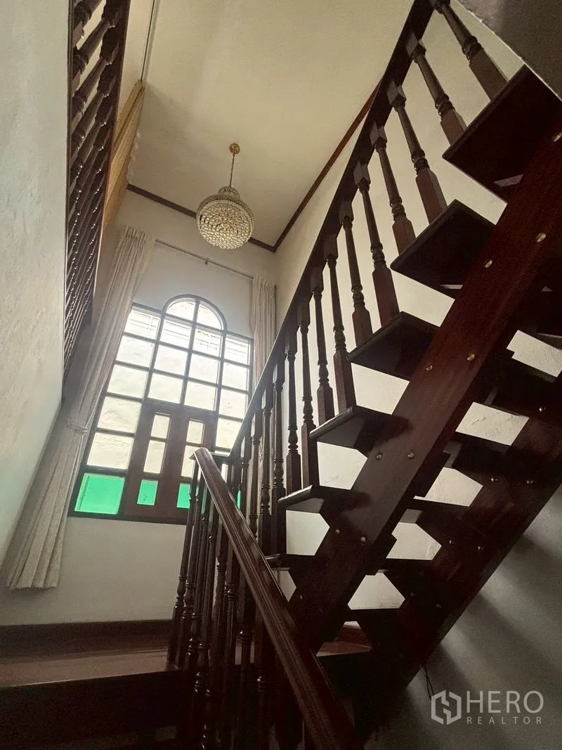 独栋房屋 for sale in Suan Luang, Bangkok - 高挑空间中的木楼梯与拱形窗户细节。