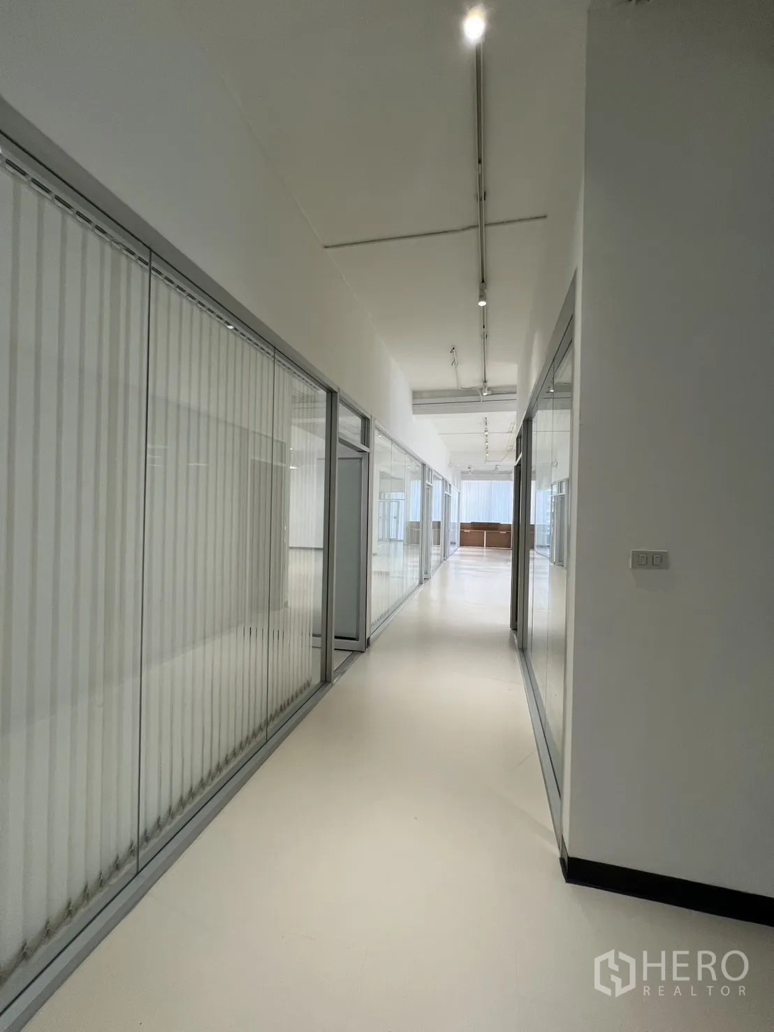 Office Space for rent in Bang Rak, Bangkok - Long hallway lined with glass partitions and vertical blinds leading to reception.