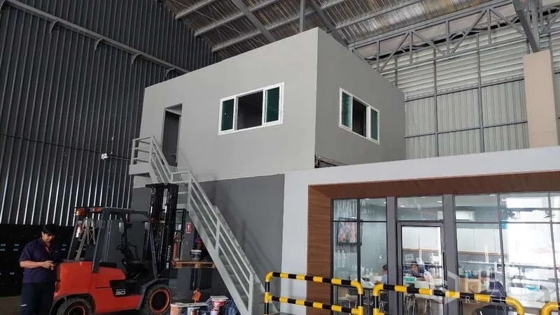 Warehouse for rent in Rat Burana, Bangkok - Warehouse mezzanine office with windows and metal stairs beside a forklift work zone and safety barriers.