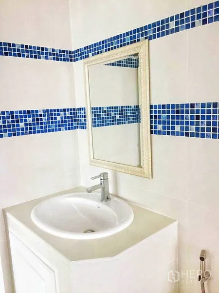 Detached House for sale in Taling Chan, Bangkok - White vanity sink with mirror and blue mosaic border.