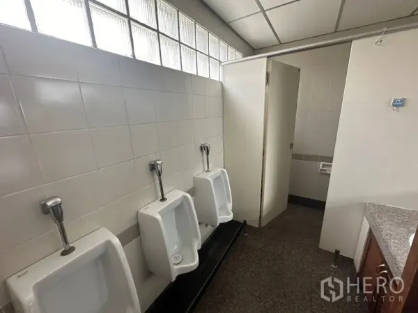 สำนักงาน ให้เช่า - ห้องน้ำชายในอาคารสำนักงาน มีโถปัสสาวะติดผนังสามจุด ผนังปูกระเบื้องและห้องส้วมแยก พร้อมช่องแสงบล็อกแก้ว