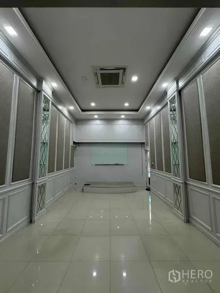 Office Space for rent in Prawet, Bangkok - Long conference room with recessed lighting, paneled walls, whiteboard and glossy tile floor.