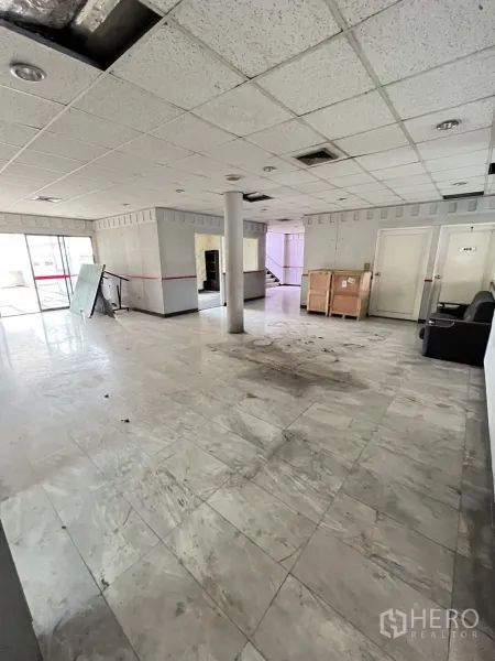 Warehouse for rent in Huai Khwang, Bangkok - Ground-floor lobby space with marble tiles and multiple doors inside the industrial building.