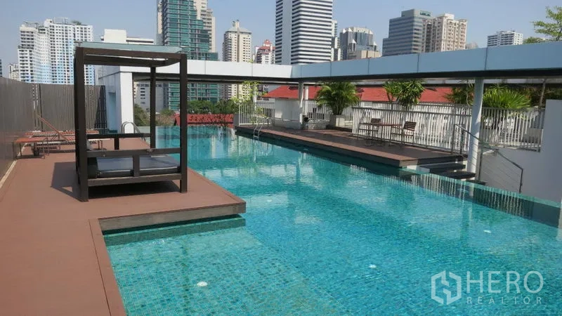 Condominium for rent or sale in Watthana, Bangkok - Rooftop swimming pool with city skyline views, sun deck and cabana seating.
