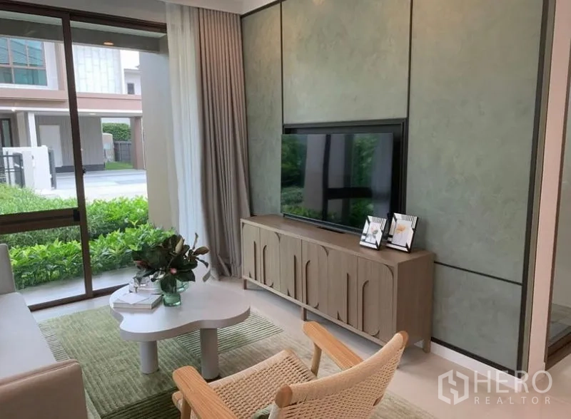 独立式住宅 出售在Bang Kapi, Bangkok - 休闲电视区，特色墙与电视柜，落地窗可欣赏花园景观。