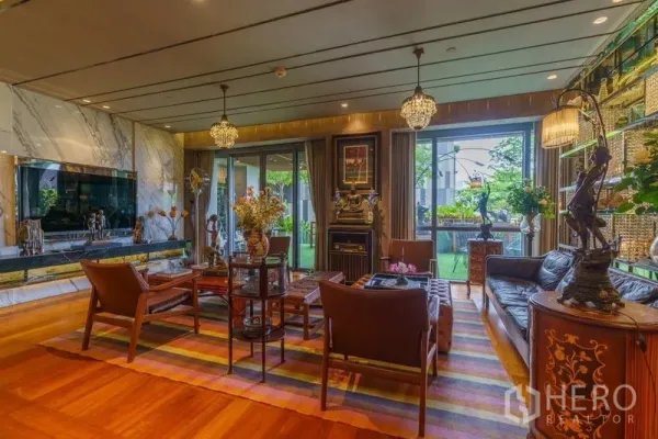 Condominium for sale in Yan Nawa, Bangkok - Luxury living room with marble feature wall, crystal chandeliers and doors to a garden terrace.