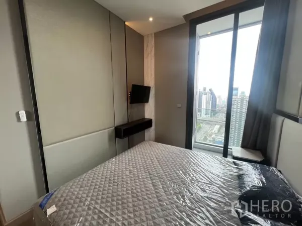 公寓 出租在Huai Khwang, Bangkok - 卧室配床与壁挂电视，推拉门通向阳台，可观城市天际线。