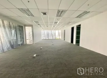 Office Space for rent - Long open workspace with carpet, ceiling lights, glass partitions and multiple floor boxes for cabling.
