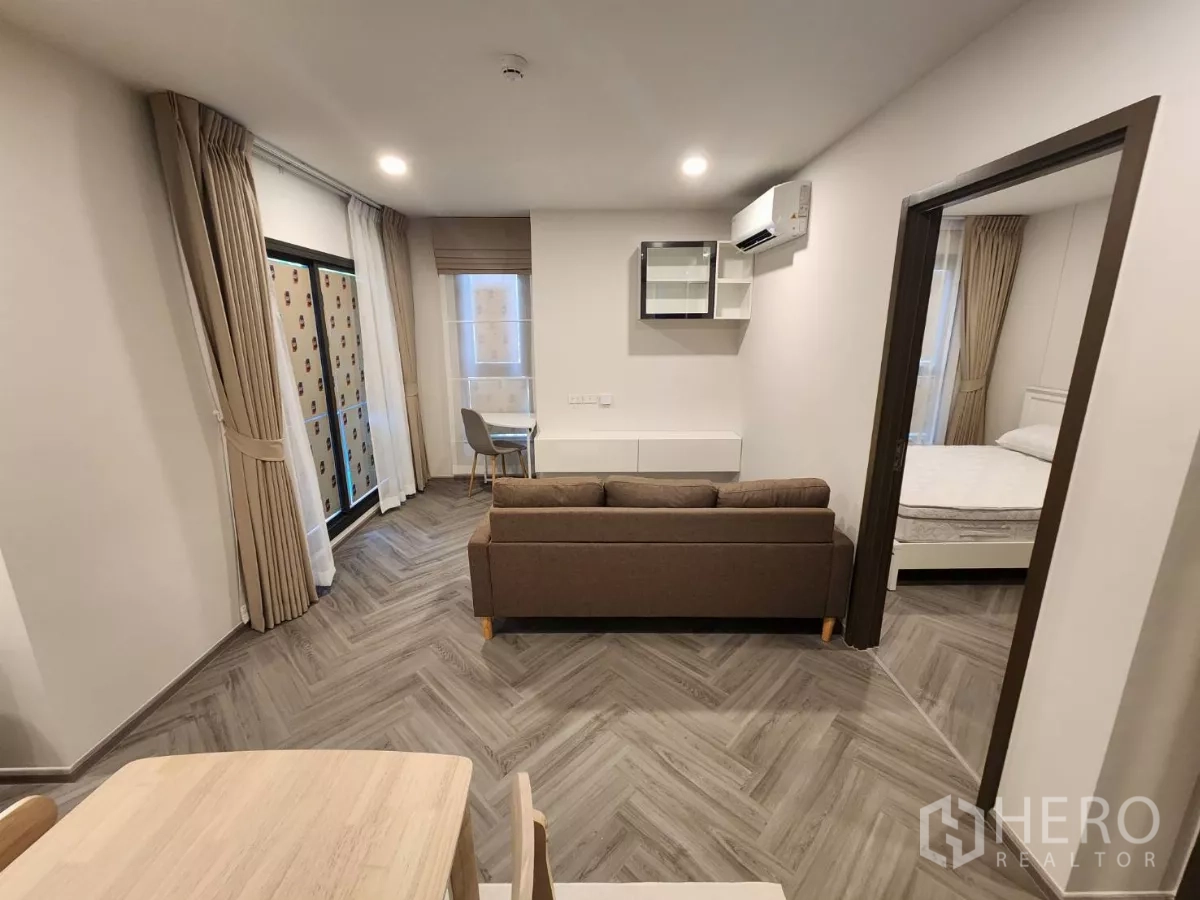 Townhouse for rent in Khlong Toei, Bangkok - Bright living room with sofa, desk nook and access to a bedroom.