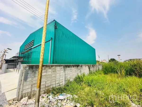 คลังสินค้า ให้เช่าในBang Phli, Samut Prakan - ภายนอกโกดังผนังเมทัลชีทสีเขียว มีช่องระบายอากาศและกำแพงรอบข้างติดพื้นที่สีเขียว