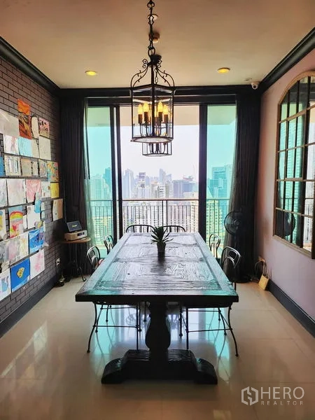 Condominium for sale in Khlong Toei, Bangkok - Dining space by floor-to-ceiling windows opening to balcony and skyline.