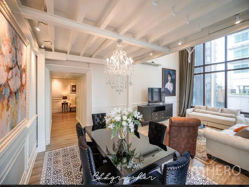 คอนโด ให้เช่าหรือขายในKhlong Toei, Bangkok - โซนรับประทานอาหารใต้เพดานคานเปลือยพร้อมโคมระย้า เชื่อมต่อห้องนั่งเล่นและผนังกระจกสูง