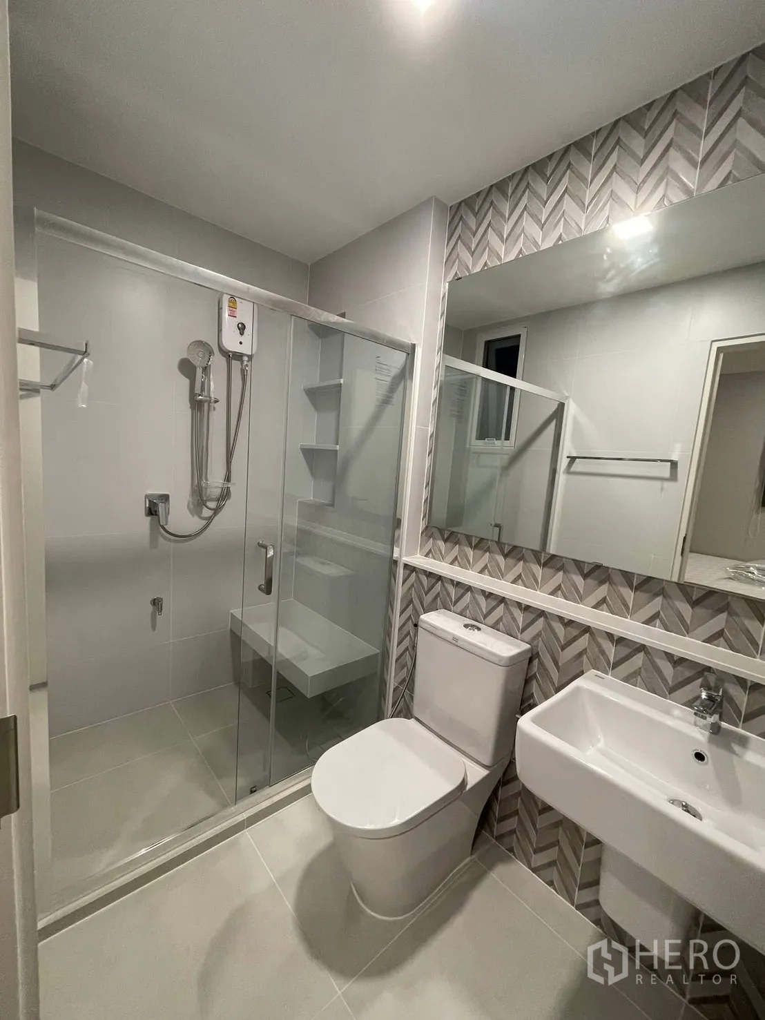 Detached House for rent in Prawet, Bangkok - Bathroom with chevron accent tiles, glass shower, and white fixtures.