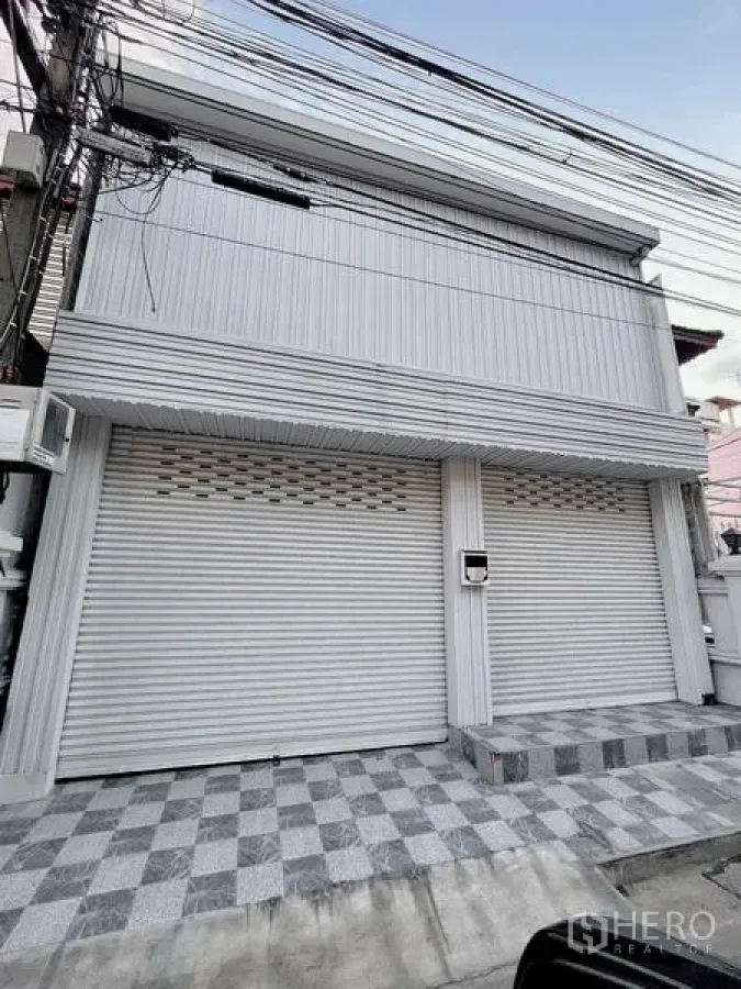 ทาวน์เฮาส์ ให้เช่าในHuai Khwang, Bangkok - ด้านหน้าทาวน์เฮ้าส์สองชั้น ม่านเหล็กม้วน และลานกระเบื้องหน้าบ้าน