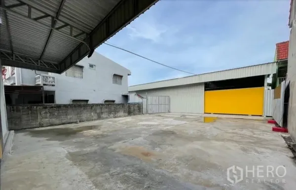 Warehouse for rent in Don Mueang, Bangkok - Concrete yard with covered loading area and steel warehouse with a yellow door in Don Mueang, Bangkok.