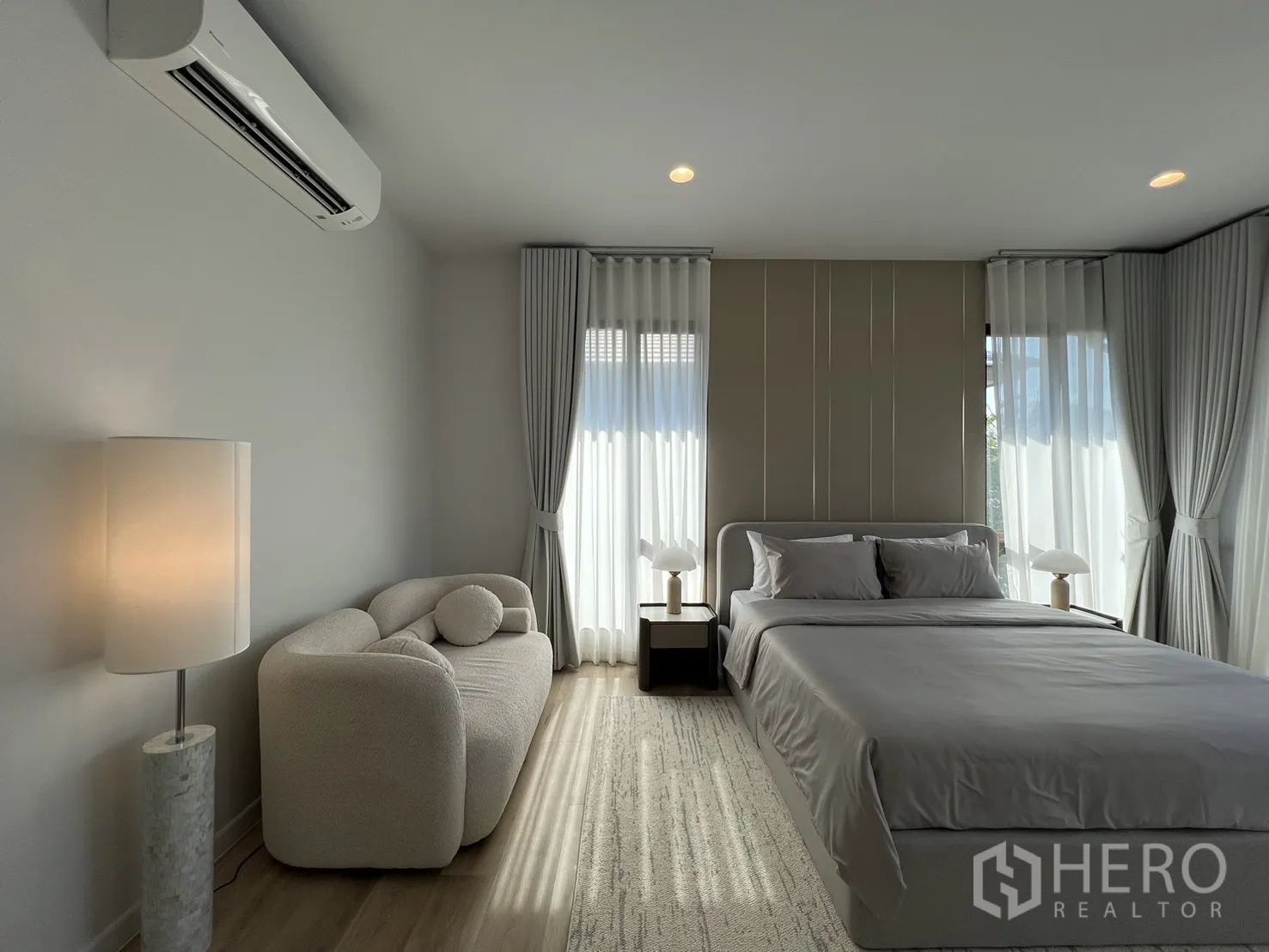 Detached House for rent or sale in Bang Kapi, Bangkok - Cozy master suite area with curved sofa, lamp and wood floors.